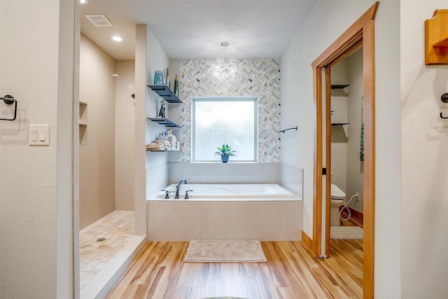 bathroom featuring an inviting chandelier, hardwood / wood-style floors, toilet, and separate shower and tub