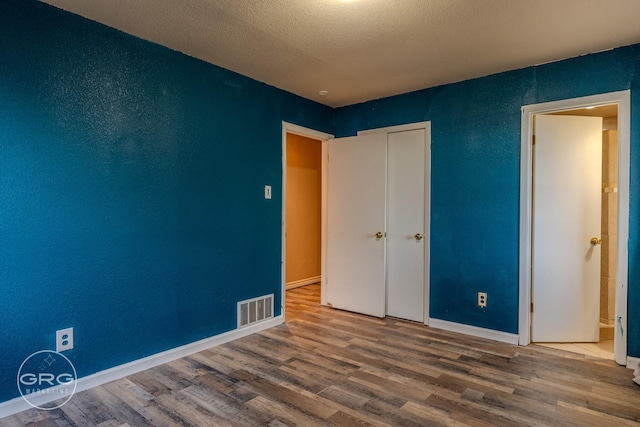 unfurnished bedroom with hardwood / wood-style floors and a textured ceiling