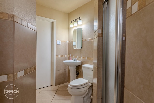 bathroom featuring tile patterned flooring, toilet, and tile walls