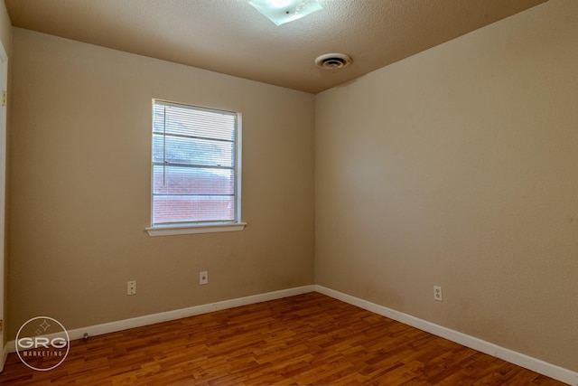 empty room featuring wood-type flooring and a textured ceiling