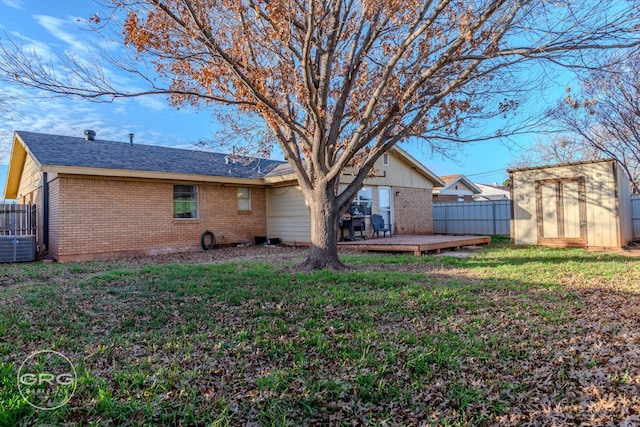 back of house with a lawn, a shed, a deck, and central AC