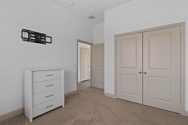 unfurnished bedroom with light colored carpet and a closet