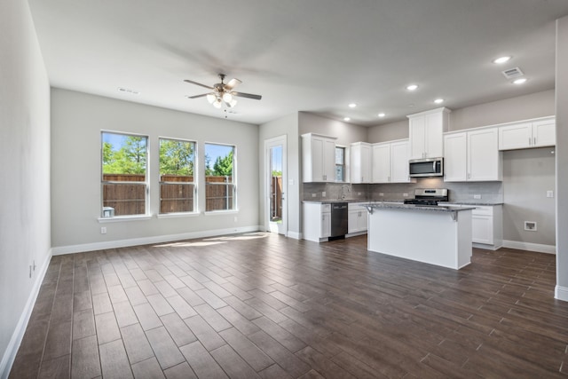 kitchen with a kitchen island, light stone counters, white cabinetry, and appliances with stainless steel finishes