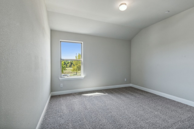 spare room featuring carpet floors and vaulted ceiling