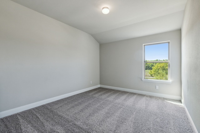 carpeted empty room with vaulted ceiling