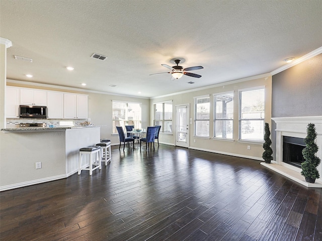 living room featuring ceiling fan, a healthy amount of sunlight, and ornamental molding