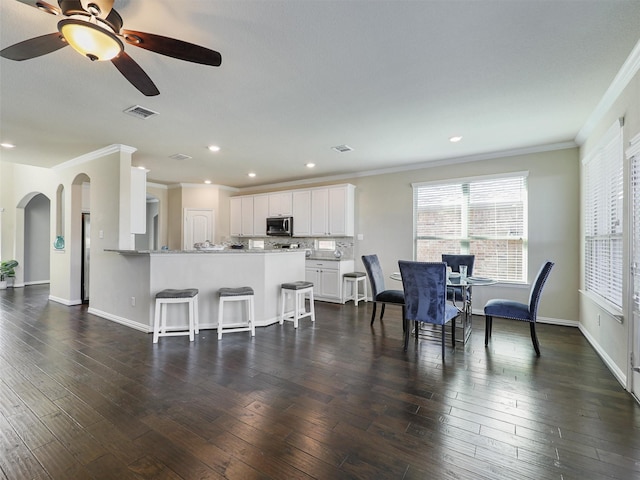 dining space featuring ceiling fan, crown molding, and dark wood-type flooring