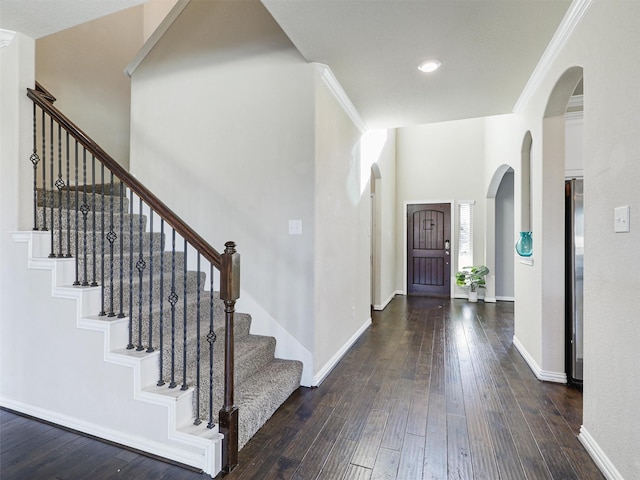 foyer entrance featuring a high ceiling, dark hardwood / wood-style flooring, and ornamental molding