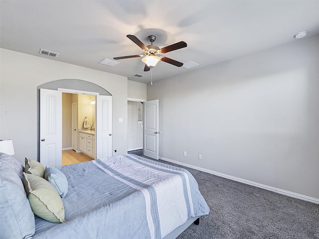 bedroom featuring light colored carpet, ceiling fan, and ensuite bathroom