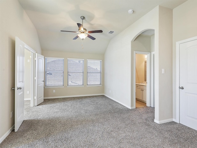 unfurnished bedroom featuring connected bathroom, ceiling fan, light colored carpet, and vaulted ceiling