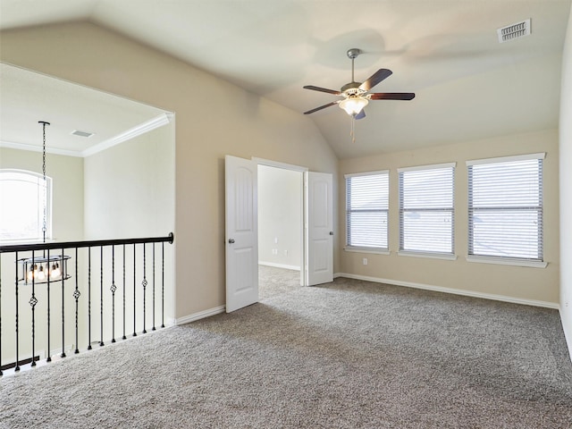 carpeted empty room featuring ceiling fan with notable chandelier, crown molding, and vaulted ceiling