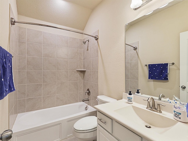 full bathroom featuring vanity, toilet, lofted ceiling, and tiled shower / bath