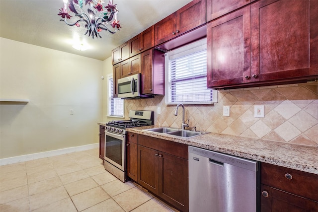 kitchen featuring backsplash, an inviting chandelier, sink, appliances with stainless steel finishes, and light tile patterned flooring