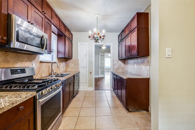 kitchen featuring hanging light fixtures, sink, light stone countertops, appliances with stainless steel finishes, and light tile patterned flooring