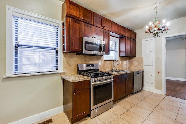 kitchen with sink, tasteful backsplash, a notable chandelier, light tile patterned flooring, and appliances with stainless steel finishes