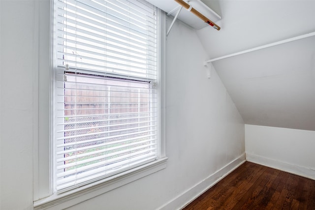 walk in closet with dark wood-type flooring and vaulted ceiling