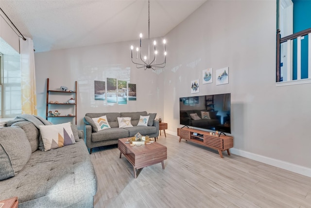 living room with a notable chandelier, light hardwood / wood-style flooring, and high vaulted ceiling