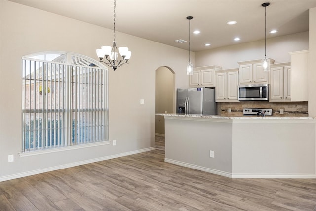 kitchen featuring backsplash, decorative light fixtures, light stone counters, and stainless steel appliances