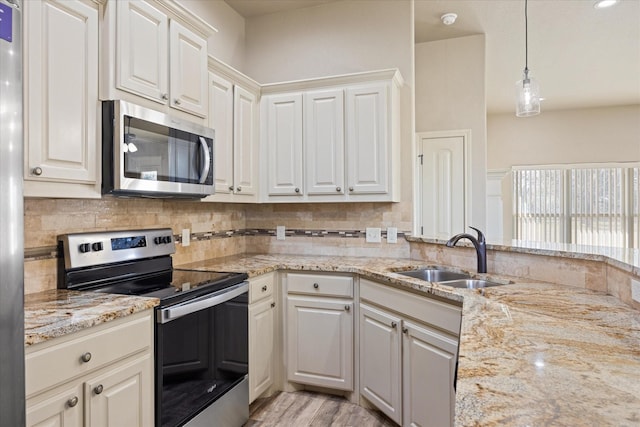 kitchen featuring sink, hanging light fixtures, decorative backsplash, white cabinetry, and stainless steel appliances