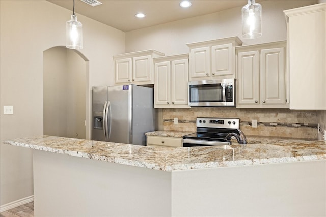 kitchen with appliances with stainless steel finishes, tasteful backsplash, light stone counters, and hanging light fixtures