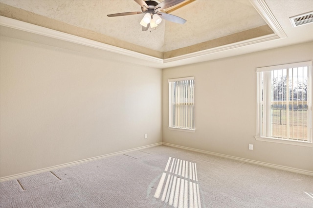 carpeted spare room featuring plenty of natural light, ceiling fan, and a raised ceiling