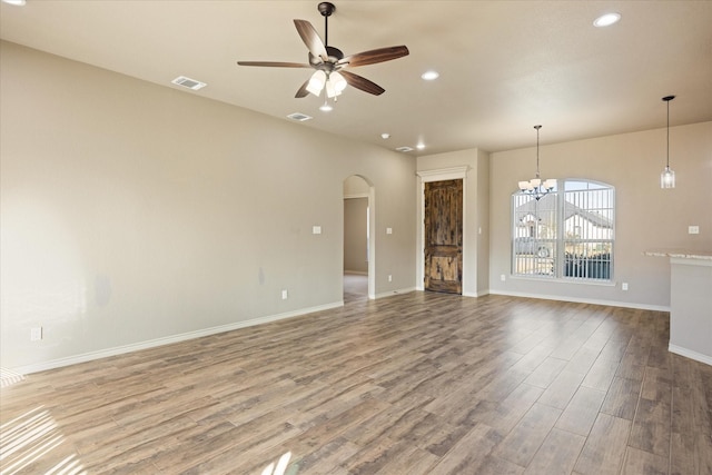 unfurnished living room with wood-type flooring and ceiling fan with notable chandelier