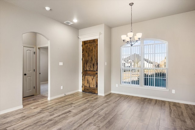 unfurnished dining area with light hardwood / wood-style flooring and a notable chandelier