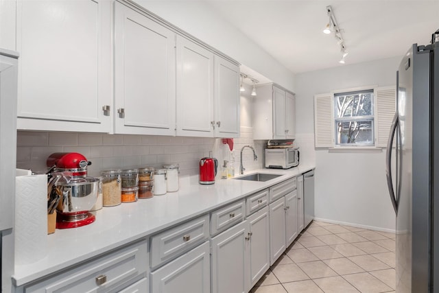 kitchen featuring backsplash, white cabinets, sink, light tile patterned floors, and stainless steel appliances