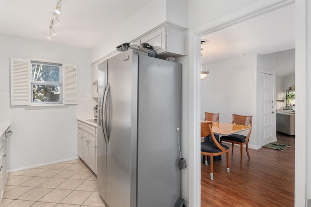 kitchen featuring white cabinets, stainless steel fridge, tasteful backsplash, and light tile patterned flooring