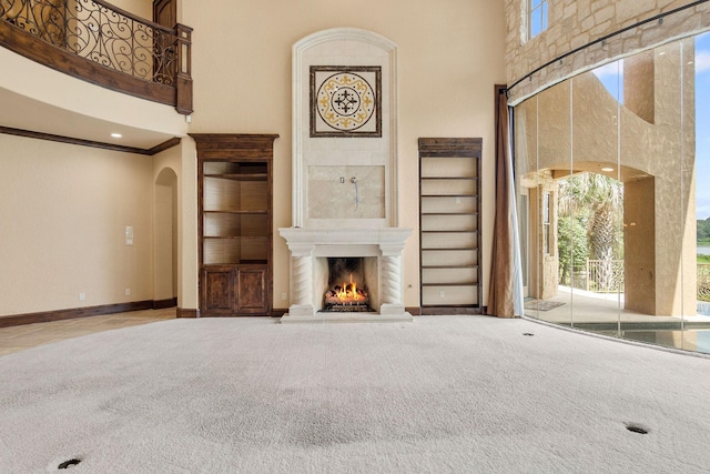 unfurnished living room featuring carpet, a towering ceiling, and a healthy amount of sunlight