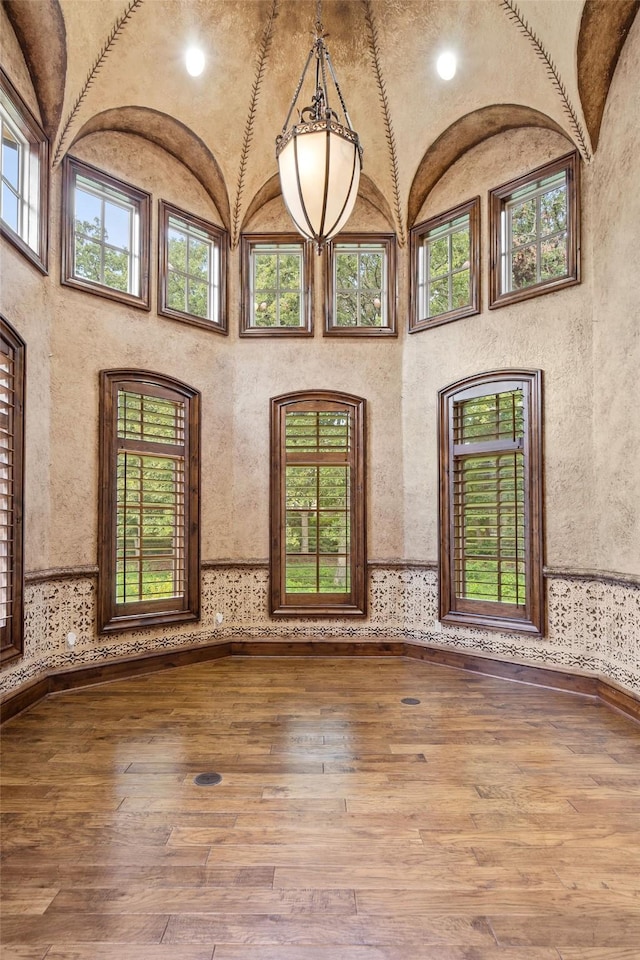 unfurnished room featuring a towering ceiling and hardwood / wood-style flooring