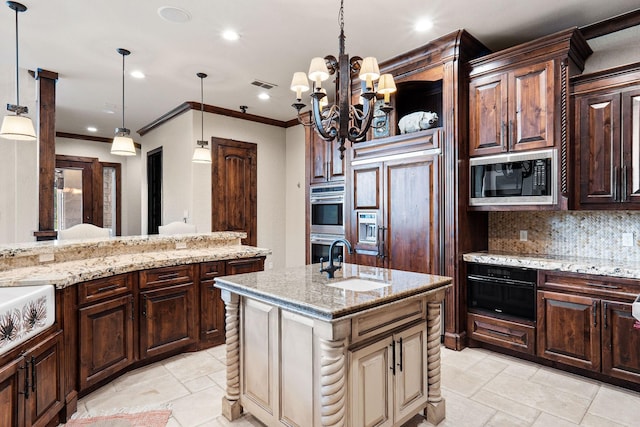 kitchen featuring sink, a notable chandelier, built in appliances, pendant lighting, and a kitchen island with sink