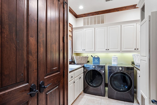 clothes washing area with washing machine and dryer, crown molding, light tile patterned flooring, and cabinets