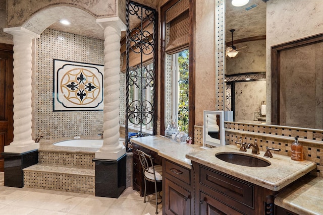 bathroom with ornate columns, ceiling fan, a washtub, and vanity