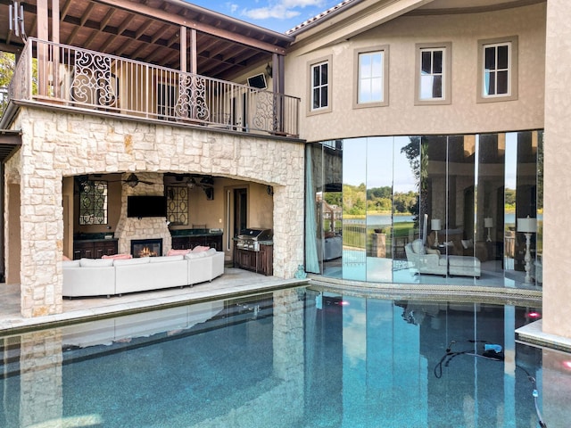 view of pool with exterior kitchen and an outdoor stone fireplace