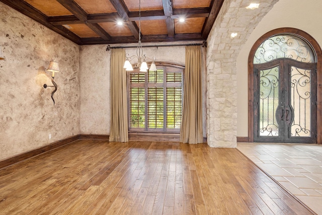 entryway with french doors, coffered ceiling, beam ceiling, light hardwood / wood-style flooring, and a notable chandelier