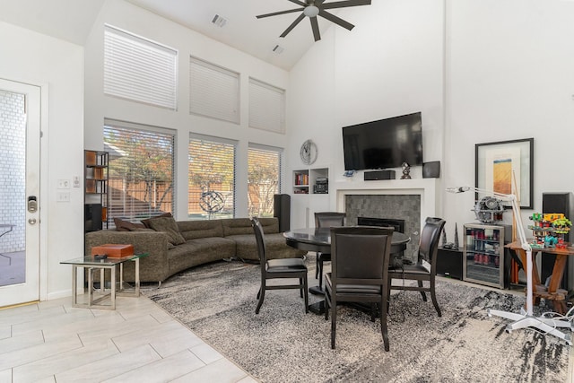 interior space with a tile fireplace, ceiling fan, high vaulted ceiling, and light tile patterned floors