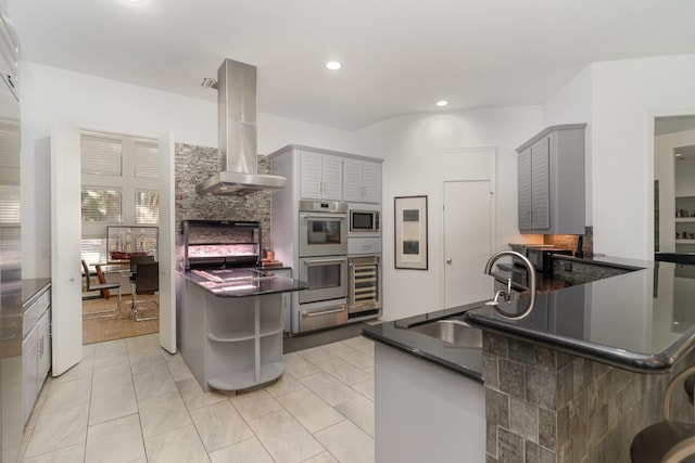 kitchen featuring kitchen peninsula, appliances with stainless steel finishes, sink, gray cabinets, and range hood