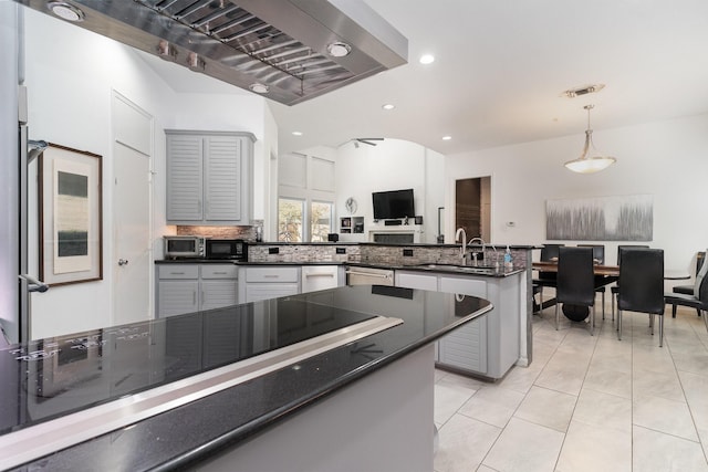 kitchen featuring gray cabinetry, backsplash, sink, hanging light fixtures, and kitchen peninsula