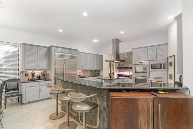 kitchen with tasteful backsplash, kitchen peninsula, and island exhaust hood