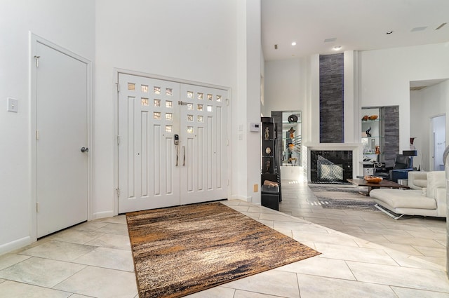 foyer with a fireplace, a towering ceiling, and light tile patterned flooring