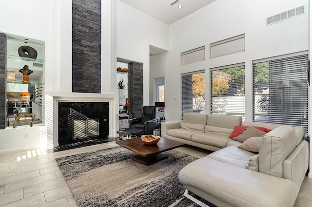 tiled living room with a fireplace and a high ceiling