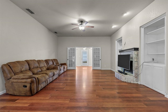 living room featuring built in shelves, dark hardwood / wood-style floors, ceiling fan, and french doors