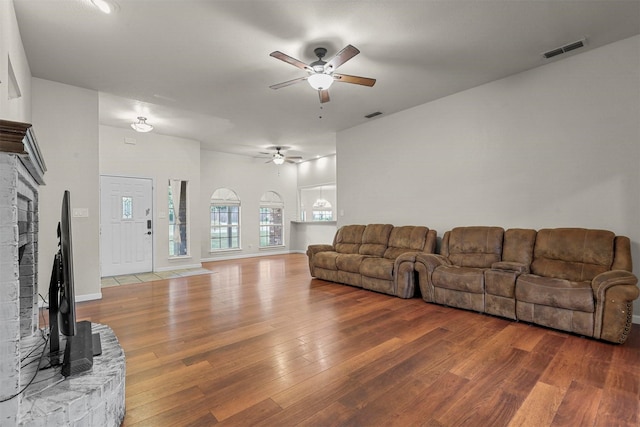 living room with a brick fireplace, hardwood / wood-style floors, and ceiling fan