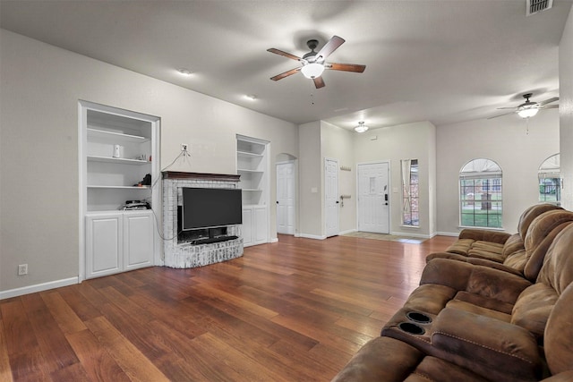 living room featuring ceiling fan, wood-type flooring, a fireplace, and built in features