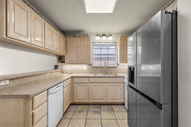 kitchen featuring dishwasher, sink, stainless steel fridge, light tile patterned floors, and light brown cabinets