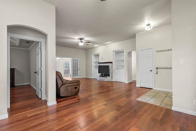 unfurnished living room with dark hardwood / wood-style floors, ceiling fan, and built in shelves