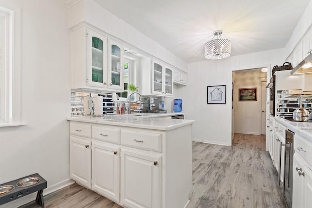 kitchen featuring sink, light hardwood / wood-style flooring, tasteful backsplash, decorative light fixtures, and white cabinetry