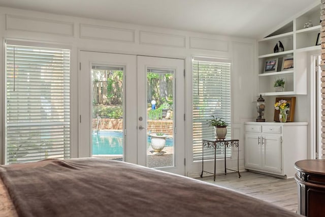 doorway with built in shelves, french doors, lofted ceiling, and light wood-type flooring