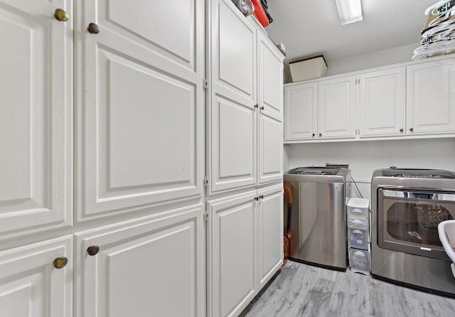 washroom featuring cabinets, light hardwood / wood-style flooring, and washer and clothes dryer